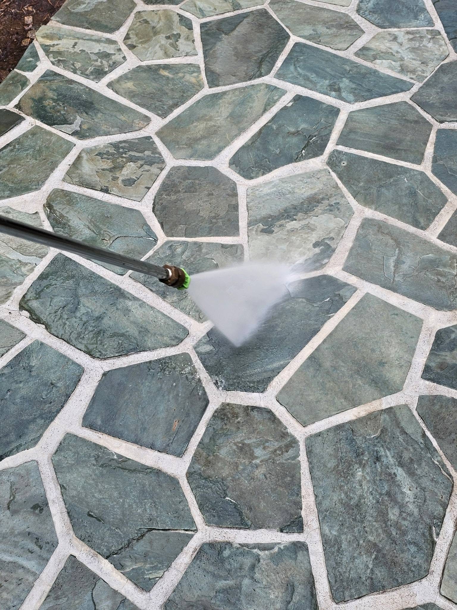 C.C. Pressure Washing rinsing a flagstone patio with a pressure washer wand