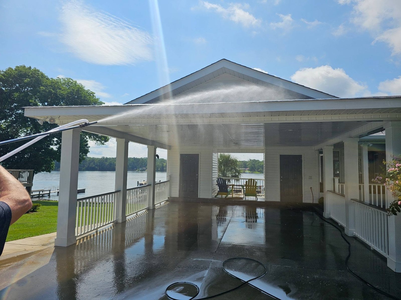 C.C. Pressure Washing spraying down a covered porch ceiling and concrete floor